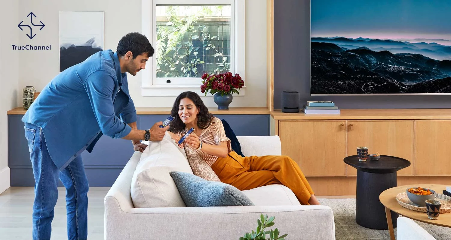 man and woman in a living room. looking at their phones together